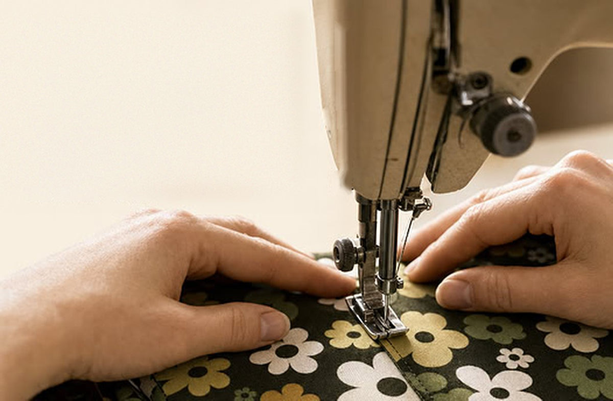 Hände nähen eine Curlix-Leggings mit Blumenmuster an der Nähmaschine