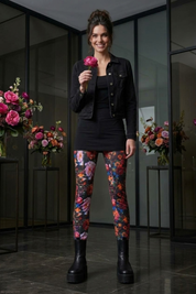 Frau in Leggins Love Baumwoll-Leggings mit Nachtwiese-Blumenmuster, schwarzem Kleid und Jacke.