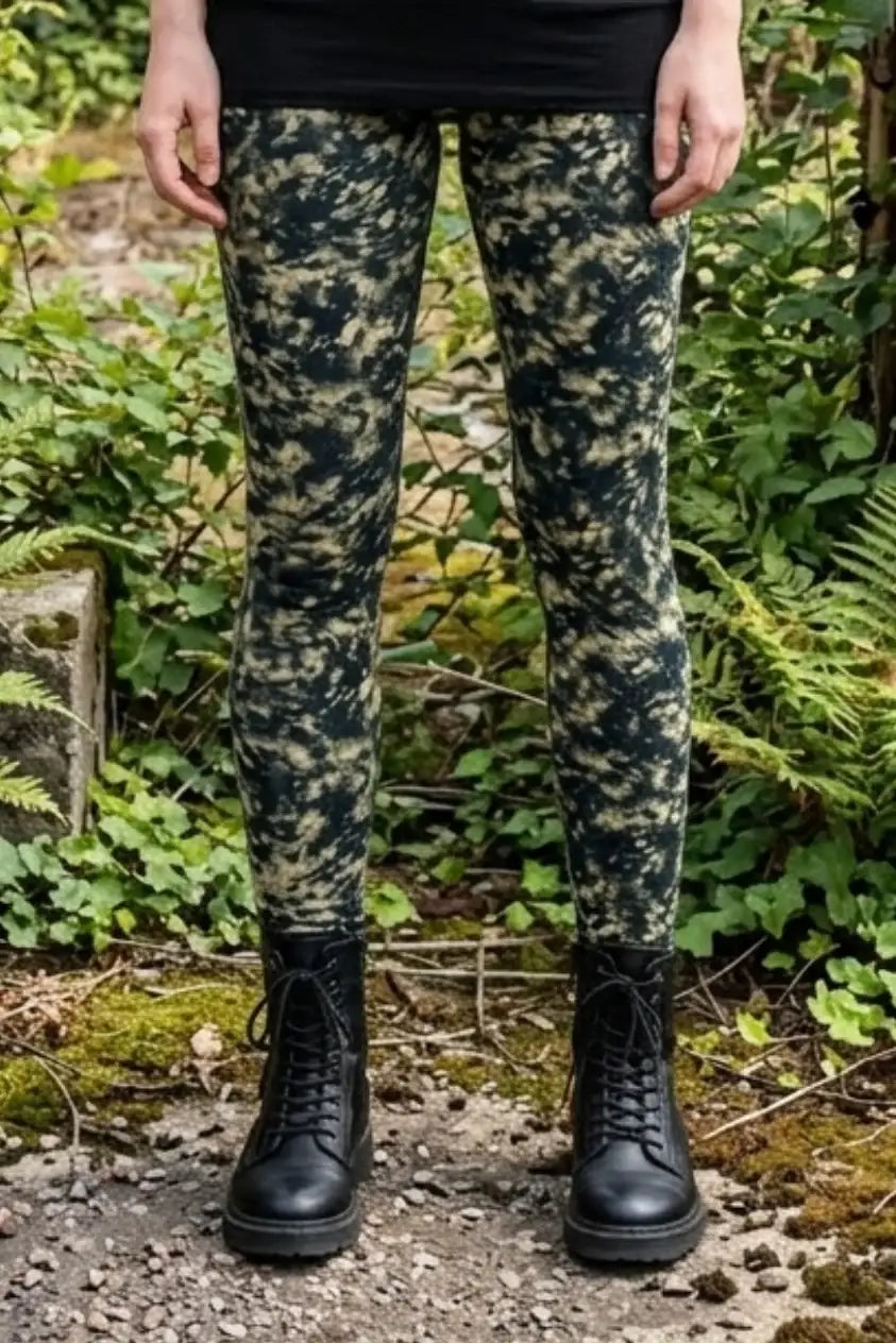 Frau trägt nachhaltige Batik-Leggings mit Stiefeln im Grünen