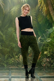 Frau trägt grüne Leoparden-Marlenehose und schwarzes Crop-Top vor Dschungel-Hintergrund