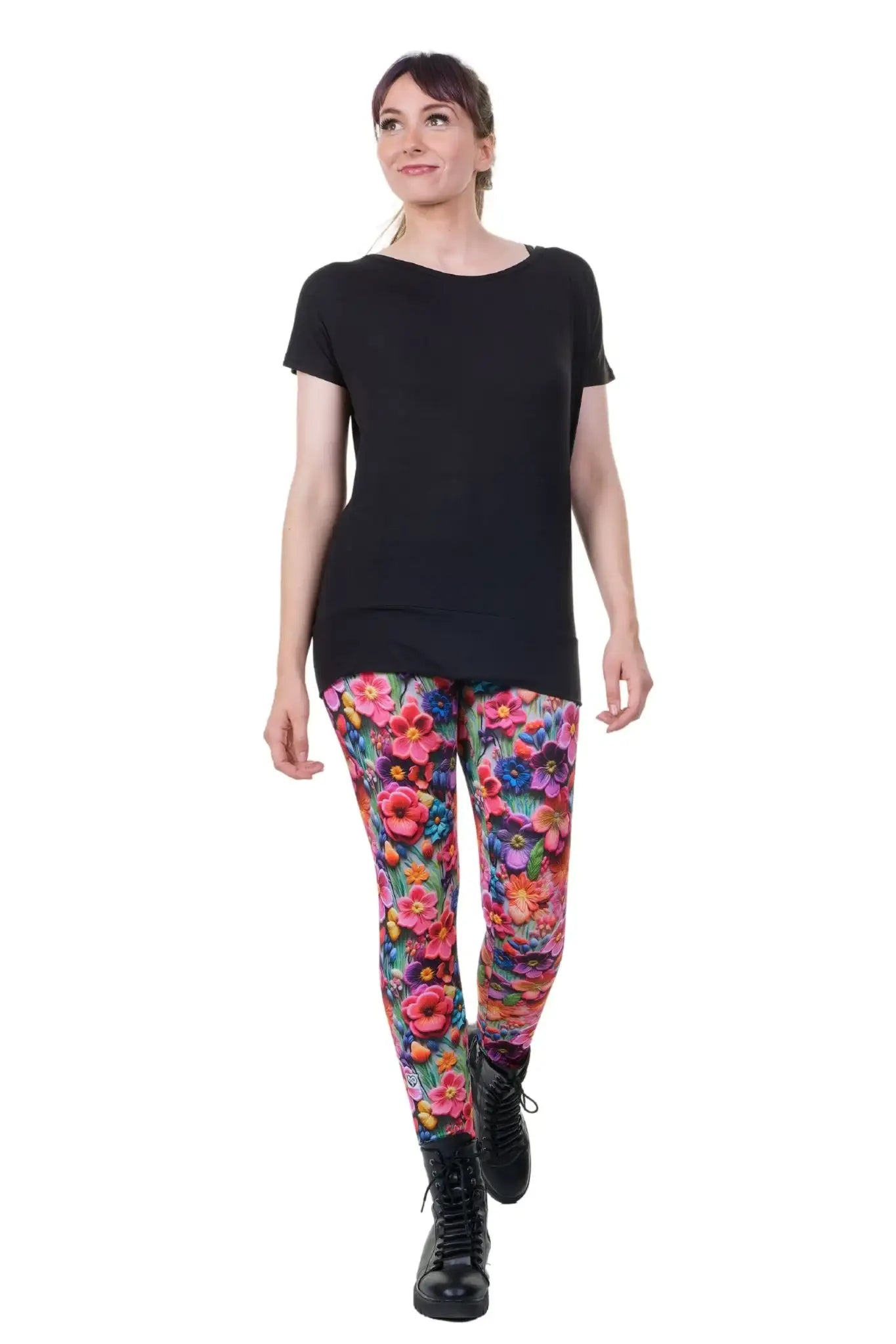 Frau trägt bunte Blumen-Leggings aus Baumwolle und schwarzes Shirt, nachhaltige Mode