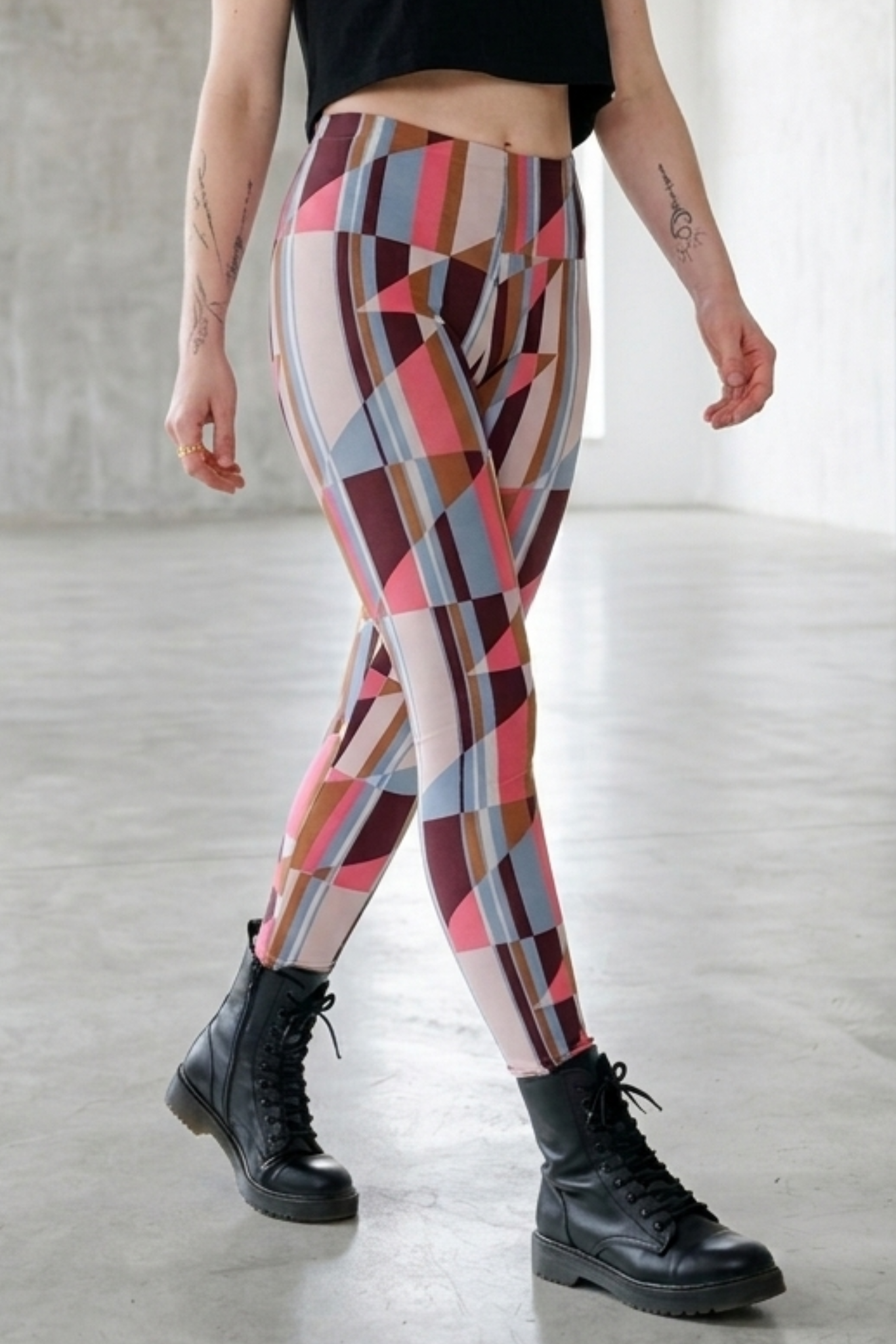 Bunte Leggings mit geometrischem Muster, getragen zu schwarzen Boots in hellem Raum