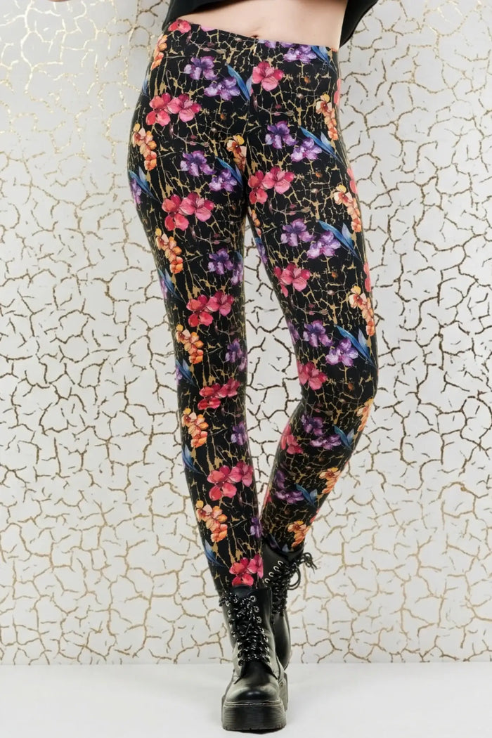 Frau trägt blickdichte Leggings mit buntem Blumenmuster vor hellem Hintergrund