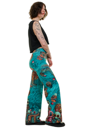 Person trägt bunte Marlenehose mit türkisfarbenem Muster und auffälligem Print, seitliche Ansicht