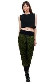 Frau trägt nachhaltige Baggy-Hose mit grünem Leopardenmuster, schwarzem Bund und schwarzem Top.