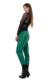 Frau trägt bunte Baggy Hose mit blau-grünem Schuppenmuster und schwarzem Mesh-Top