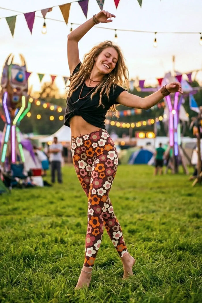 Frau tanzt barfuß auf Festivalwiese in bunter Blumen-Leggings und schwarzem T-Shirt, Sommer