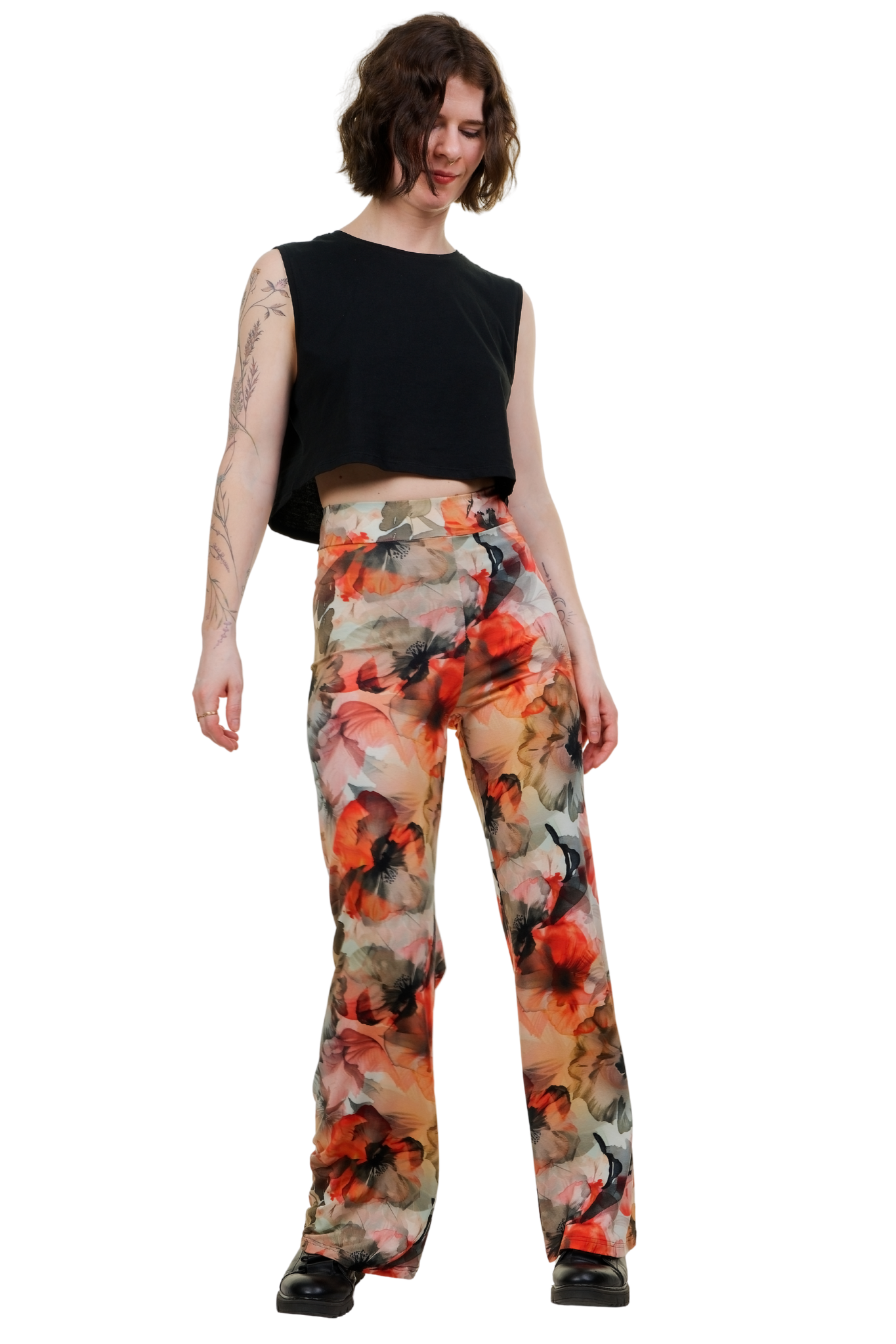 Marlene Hose für Damen mit weitem Bein und auffälligem Aquarell-Blütenprint in Orange und Rot. Die High-Waist Stoffhose von Curlix Leggins-Love fällt fließend bis zum Boden und wird von einem Model getragen. Die detaillierten Blumentattoos am Arm des Models unterstreichen den alternativen Look.