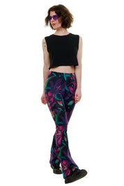 Frau mit schwarzem Crop Top, bunter Blumen-Leggings und lila Sonnenbrille auf weißem Hintergrund