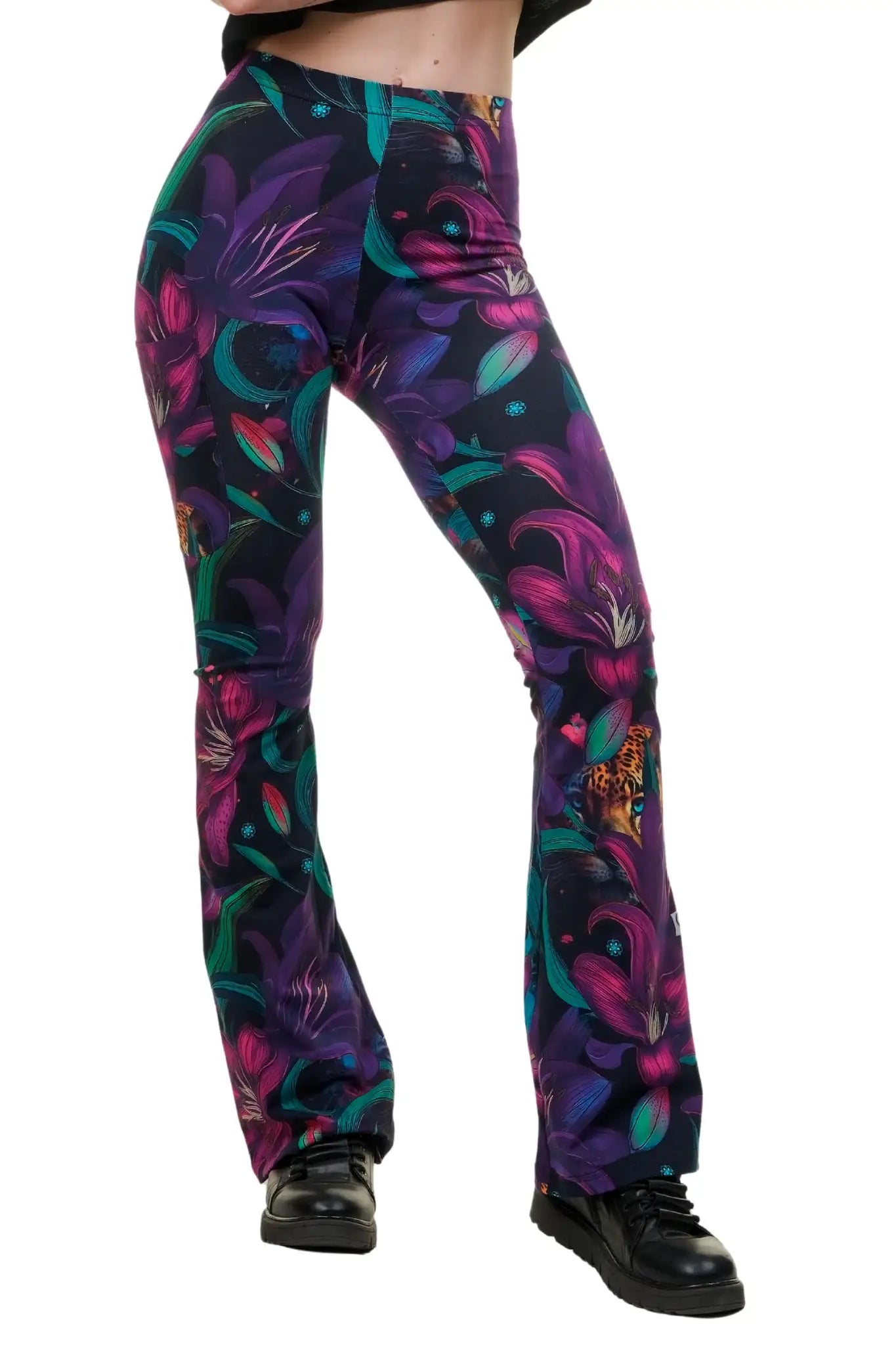 Frau trägt bunte Flared-Leggings mit lila Blumenmuster und Leoparden auf weißem Hintergrund