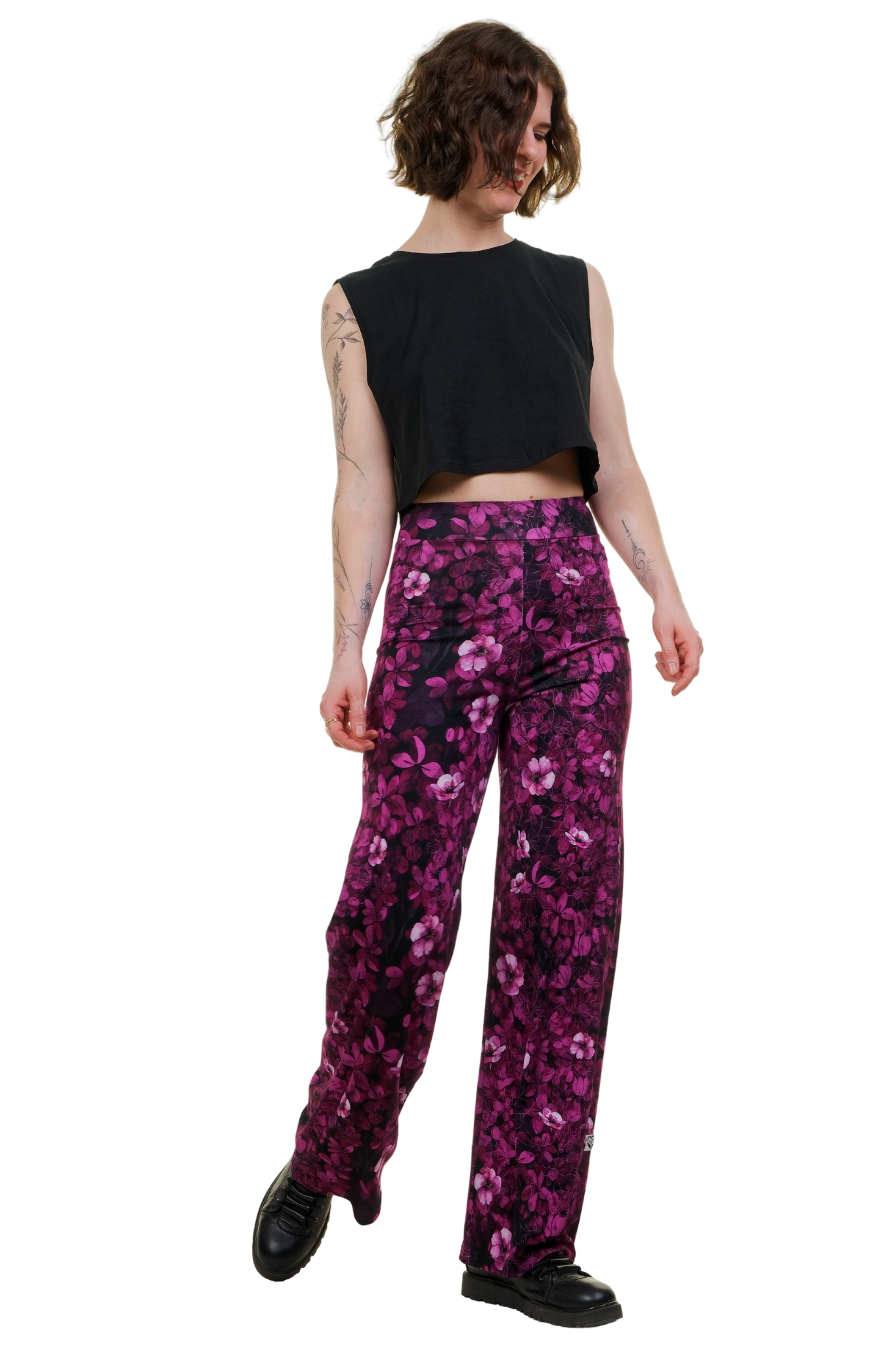 Frau trägt weite Hose mit pinkem Blumenmuster, kombiniert mit schwarzem Crop-Top