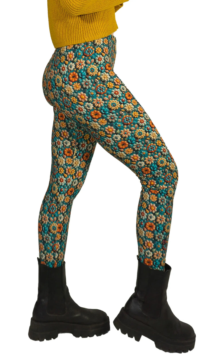 Bunte Leggings mit Blumenmuster, kombiniert mit schwarzen Boots und gelbem Strickpullover