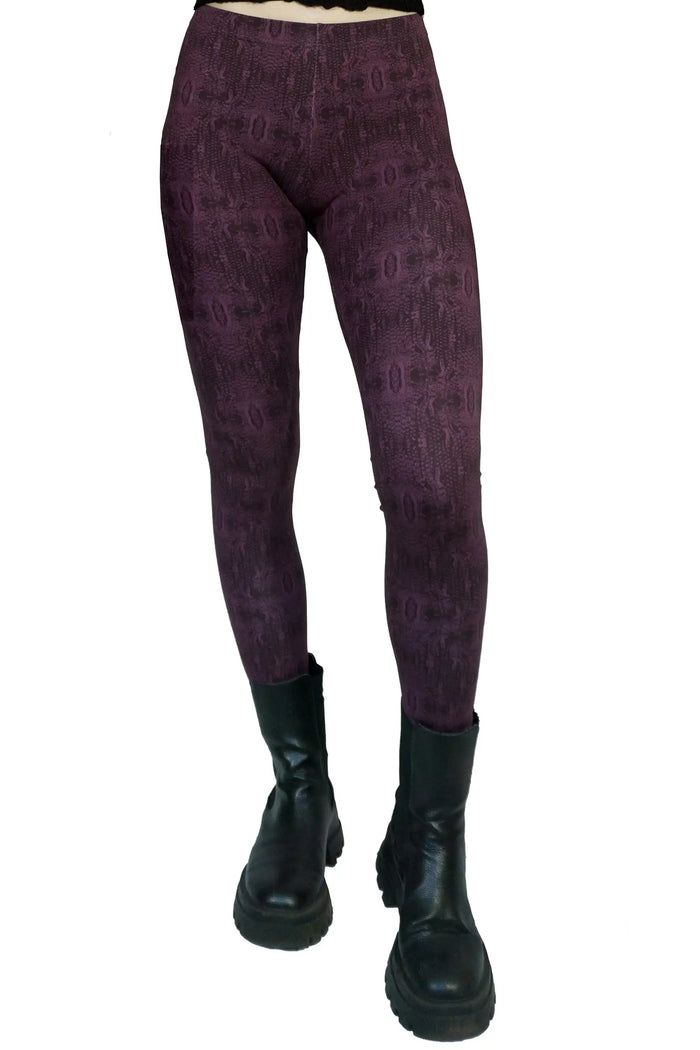 Lila Leggings mit Muster aus Baumwolle, kombiniert mit schwarzen Stiefeln, vor weißem Hintergrund.