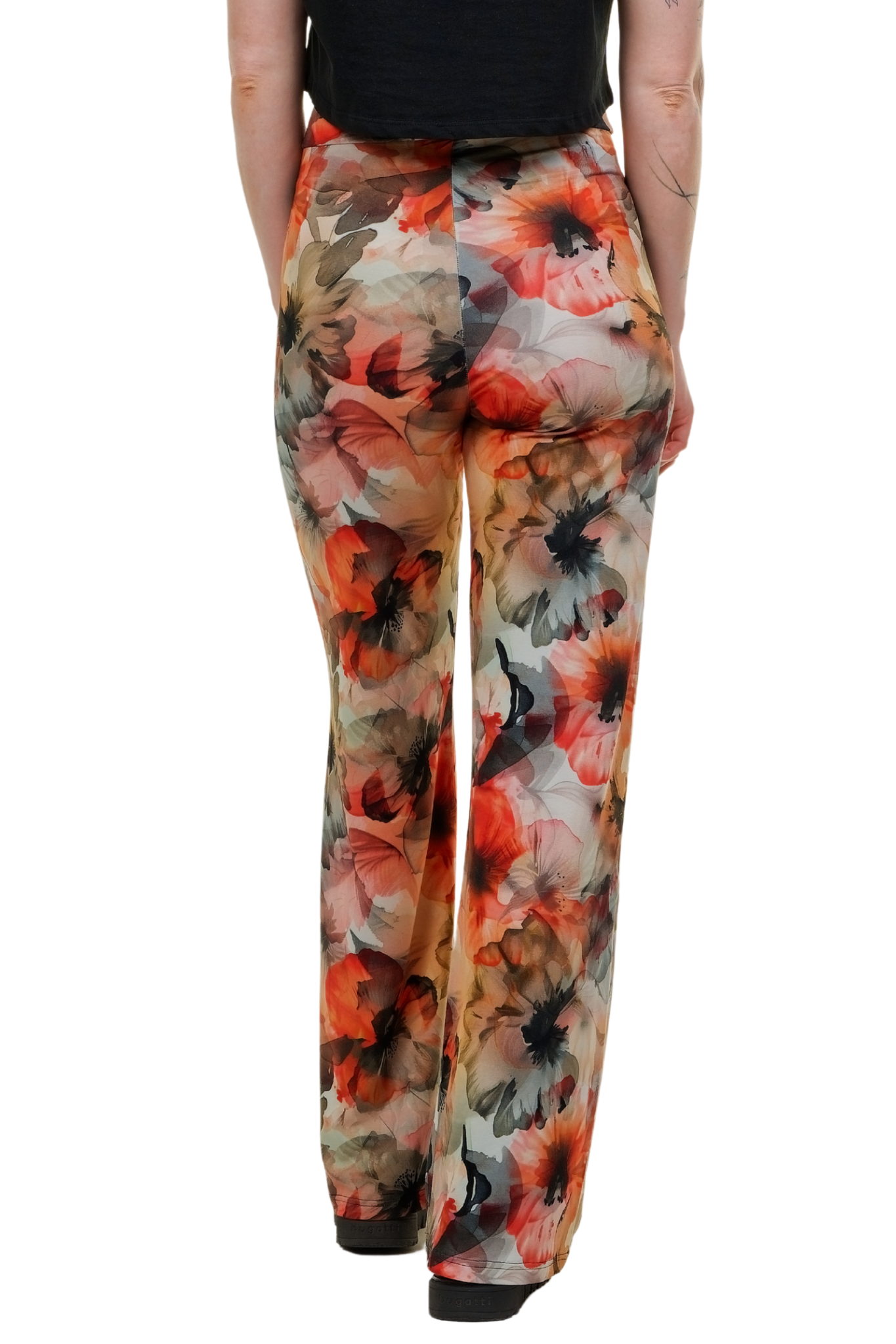 Stylische Wide-Leg Hose ,Blütenhauch' von Curlix mit floralem Muster in Herbstfarben, getragen von einem Model mit schwarzem Top und Boots vor weißem Hintergrund