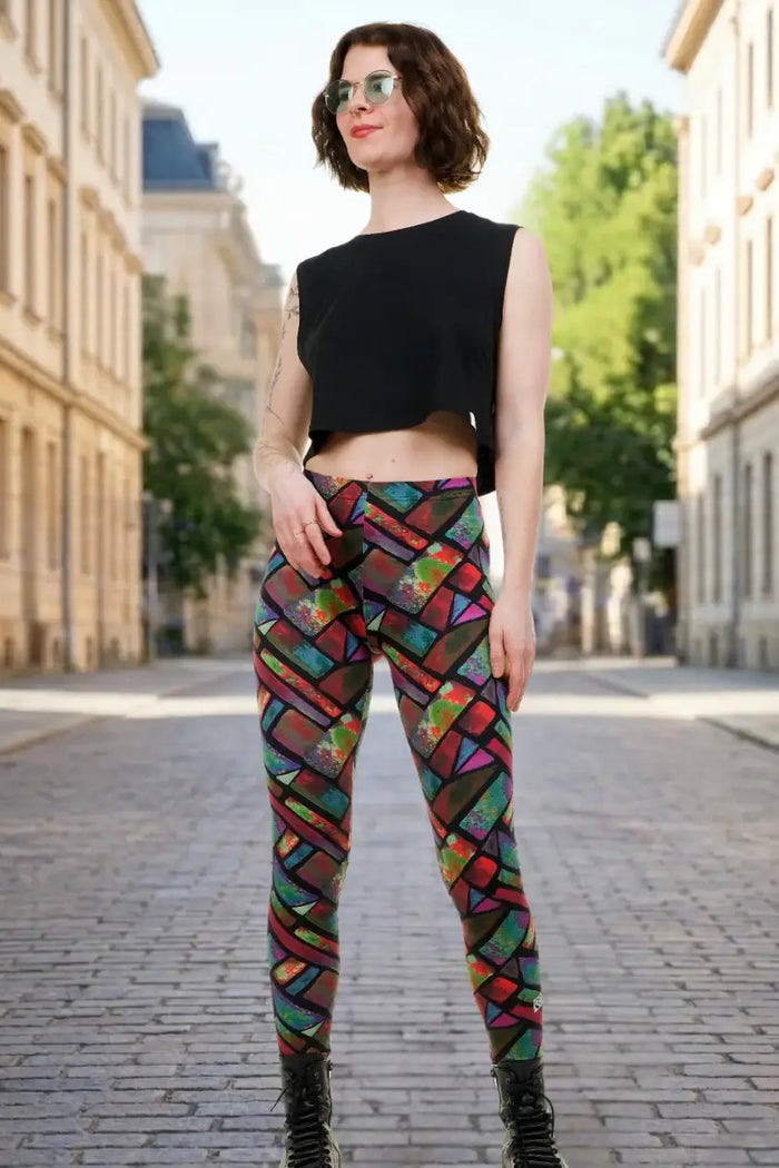 Frau mit bunter Mosaik-Leggings und schwarzem Crop-Top auf Kopfsteinpflaster-Straße