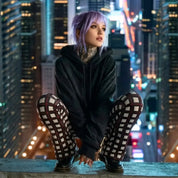 Frau mit ausgefallenen Schlagleggings mit Taschen aus Baumwolle, sitzt auf Hochhausdach in der Stadt