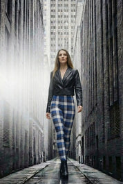 Frau in blauen Karomuster-Leggings und schwarzer Lederjacke läuft durch urbane Gasse