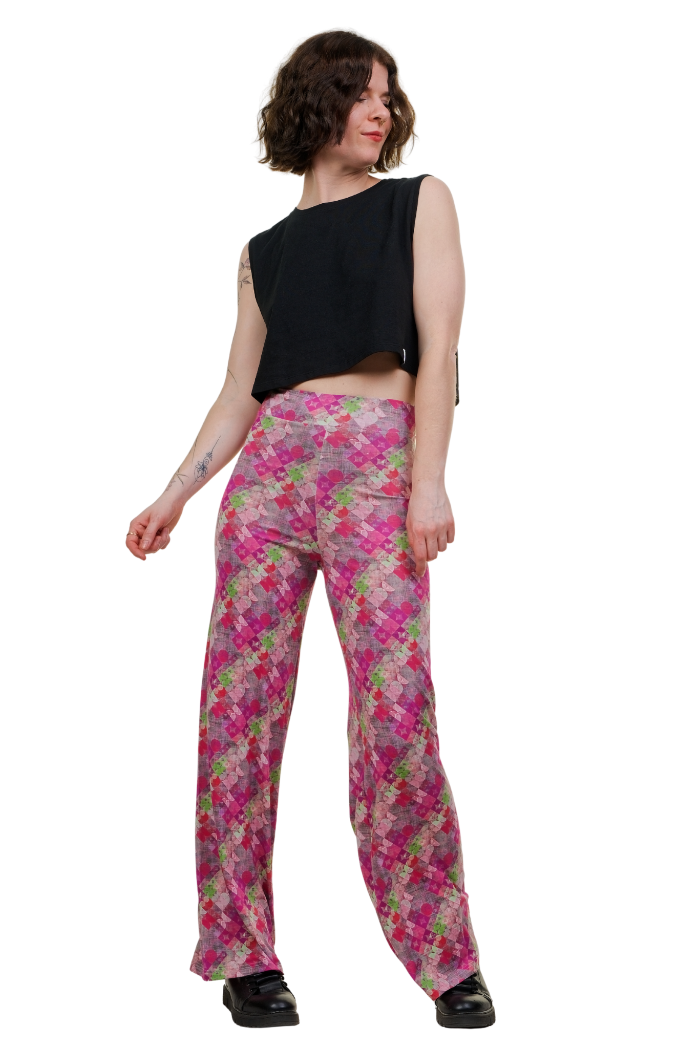 Marlene Hose Vintage Vibe Pink von Curlix mit weitem Bein und geometrischem Muster in Pink, Magenta und Grün. Ein Model trägt die High-Waist Hose kombiniert mit schwarzen Boots und einem schwarzen Crop-Top.