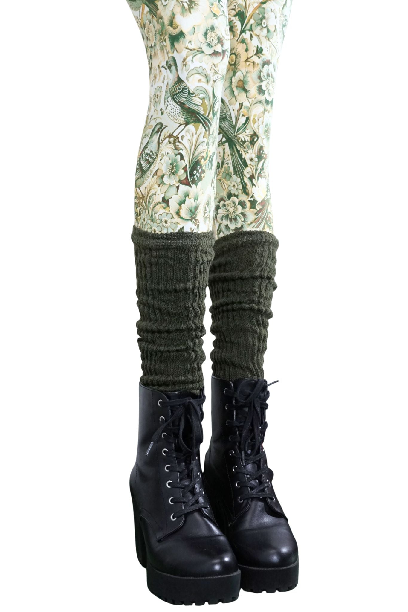 Olivgrüne Stulpen aus Strick, getragen über gemusterter Leggings und schwarzen Stiefeln