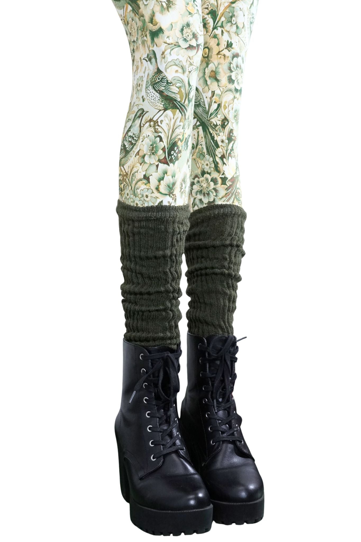 Olivgrüne Stulpen aus Strick, getragen über gemusterter Leggings und schwarzen Stiefeln