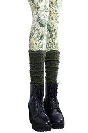 Olivgrüne Stulpen aus Strick, getragen über gemusterter Leggings und schwarzen Stiefeln