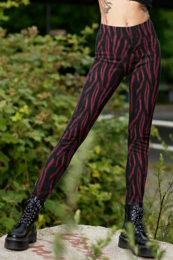 Frau trägt schwarze Leggings mit pinkem Zebramuster im Freien, kombiniert mit Plateaustiefeln